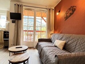 A cozy living room with a sofa, a small round table, and a television mounted on the wall.