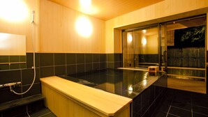 Ein modernes Badezimmer mit einer Holzbank, einer Duschkabine aus Glas und einem schwarzen Fliesenboden.