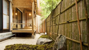 Ein traditionelles japanisches Gebäude mit Holzfassade, einem Kiesweg und einem Bambuszaun.