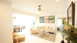 Un salón amplio con sofá, mesa de centro y zona de comedor al fondo.