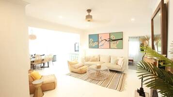 A spacious living room with a sofa, coffee table, and a dining area in the background.