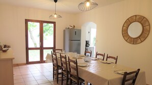 A dining area with a table set for six, wooden chairs, a chandelier, a refrigerator, and a large mirror on the wall. - Maison Spacieuse sur le Bassin D'arcachon (Lanton)