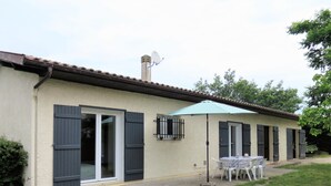 A house with a patio, a table with chairs, and a satellite dish. - Maison Spacieuse sur le Bassin D'arcachon (Lanton)