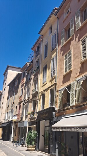 A row of traditional European buildings with shutters, a bicycle, and a sign for 'Maison Regard.'