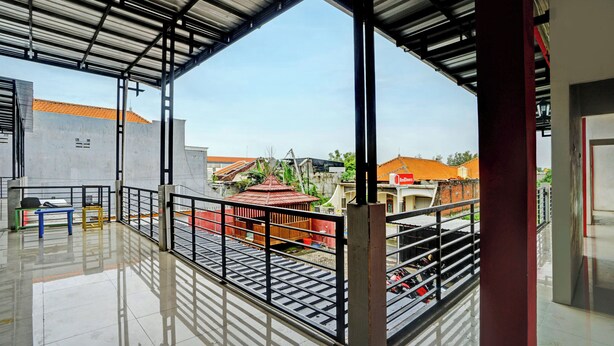 A covered outdoor area with a metal roof, a metal railing, and a view of buildings in the background. - Super OYO 3702 Homestay Bougenville Syariah (Lamongan)