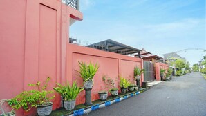 A street with a row of potted plants along a pink building. - Super OYO 3702 Homestay Bougenville Syariah (Lamongan)