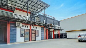 A building with a covered entrance, a car parked in front, and a clear sky. - Super OYO 3702 Homestay Bougenville Syariah (Lamongan)