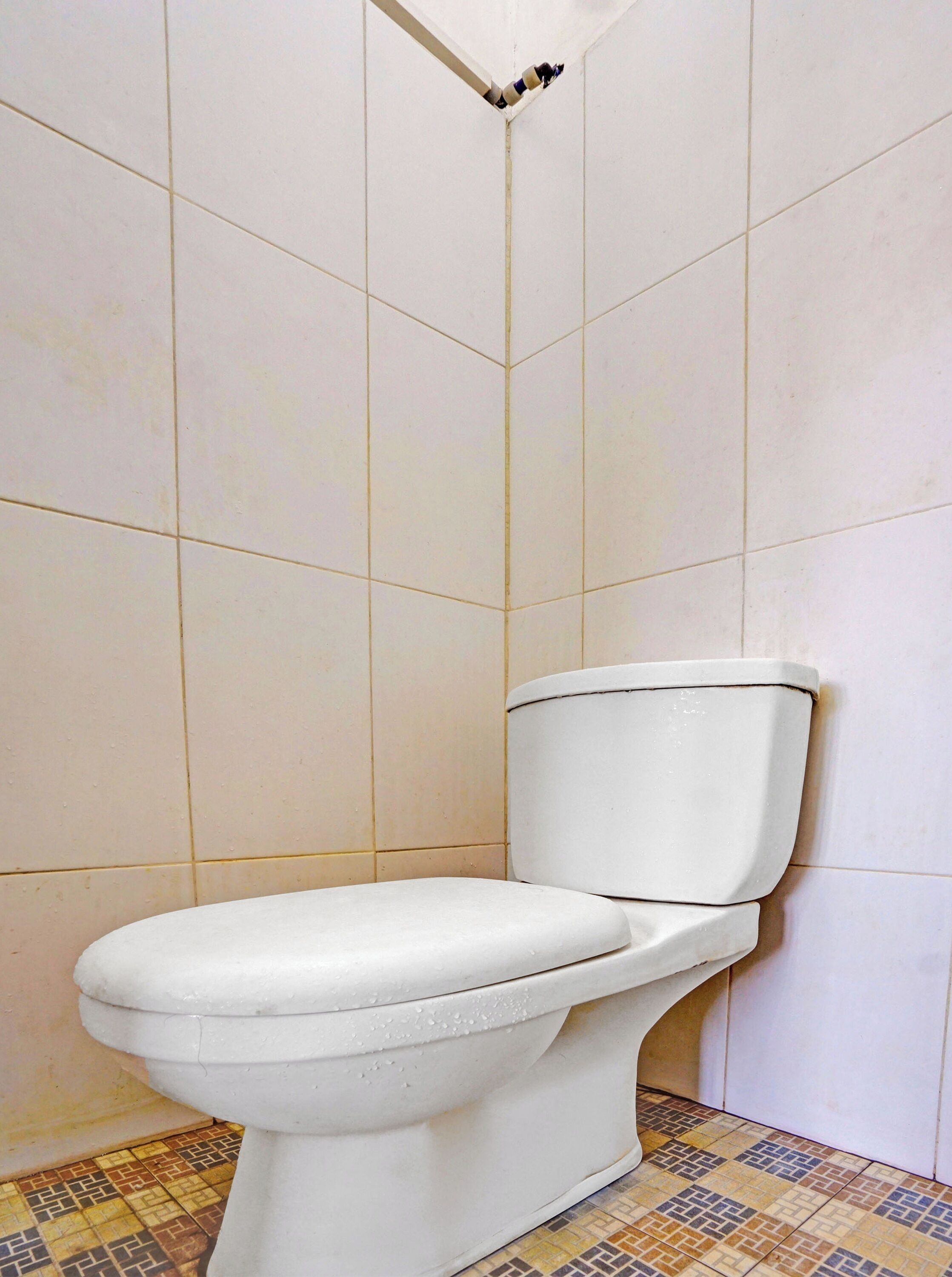 A toilet in a bathroom with tiled walls and a patterned floor.