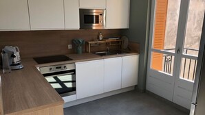 Ett modernt kök med vita skåp, en mikrovågsugn i rostfritt stål, en inbyggd ugn och en diskho.