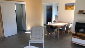 Ett modernt vardagsrum med en matplats, en soffa, en tv och en tavla på väggen.