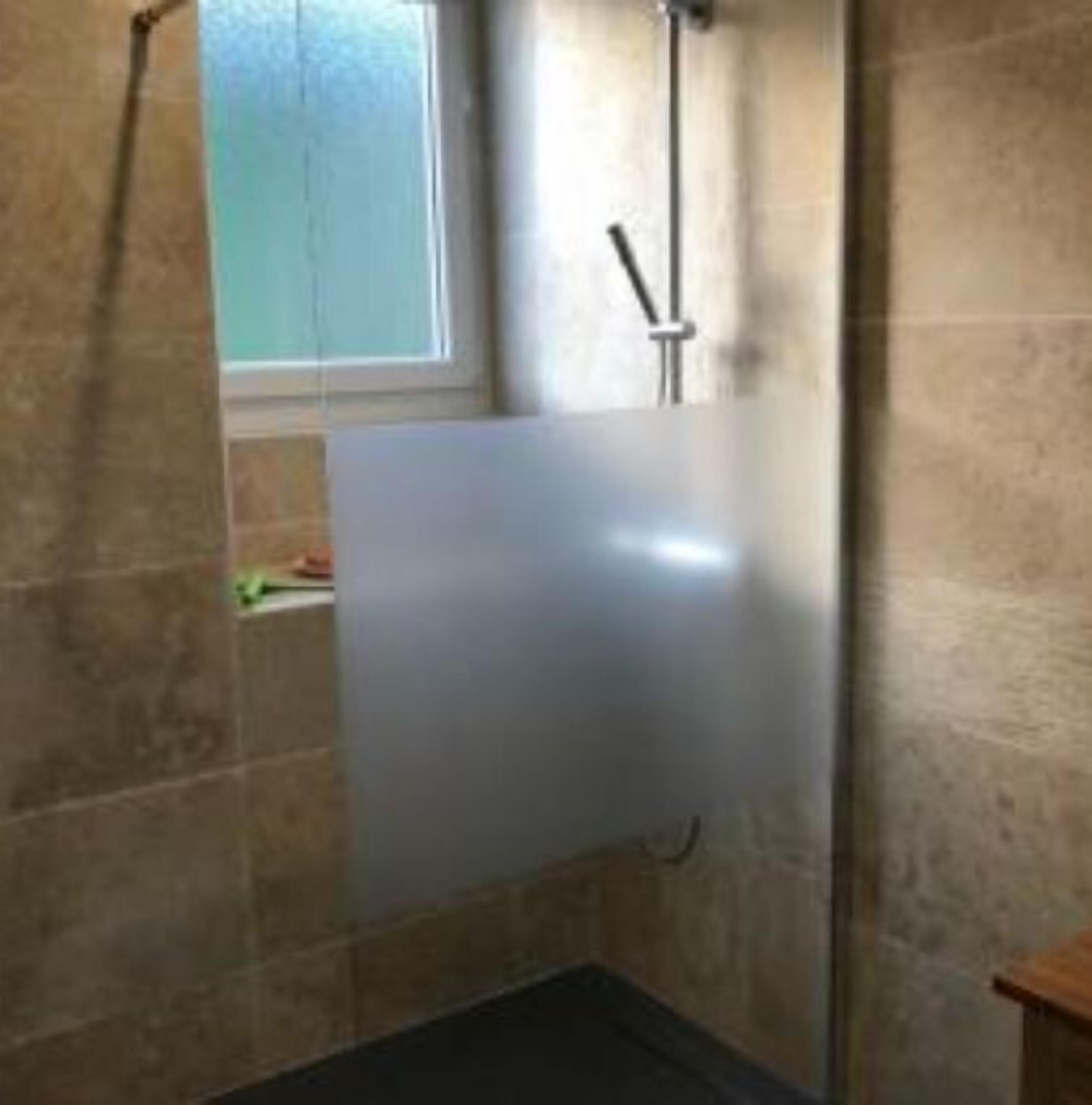 A bathroom with a bathtub, a window, and a shower.