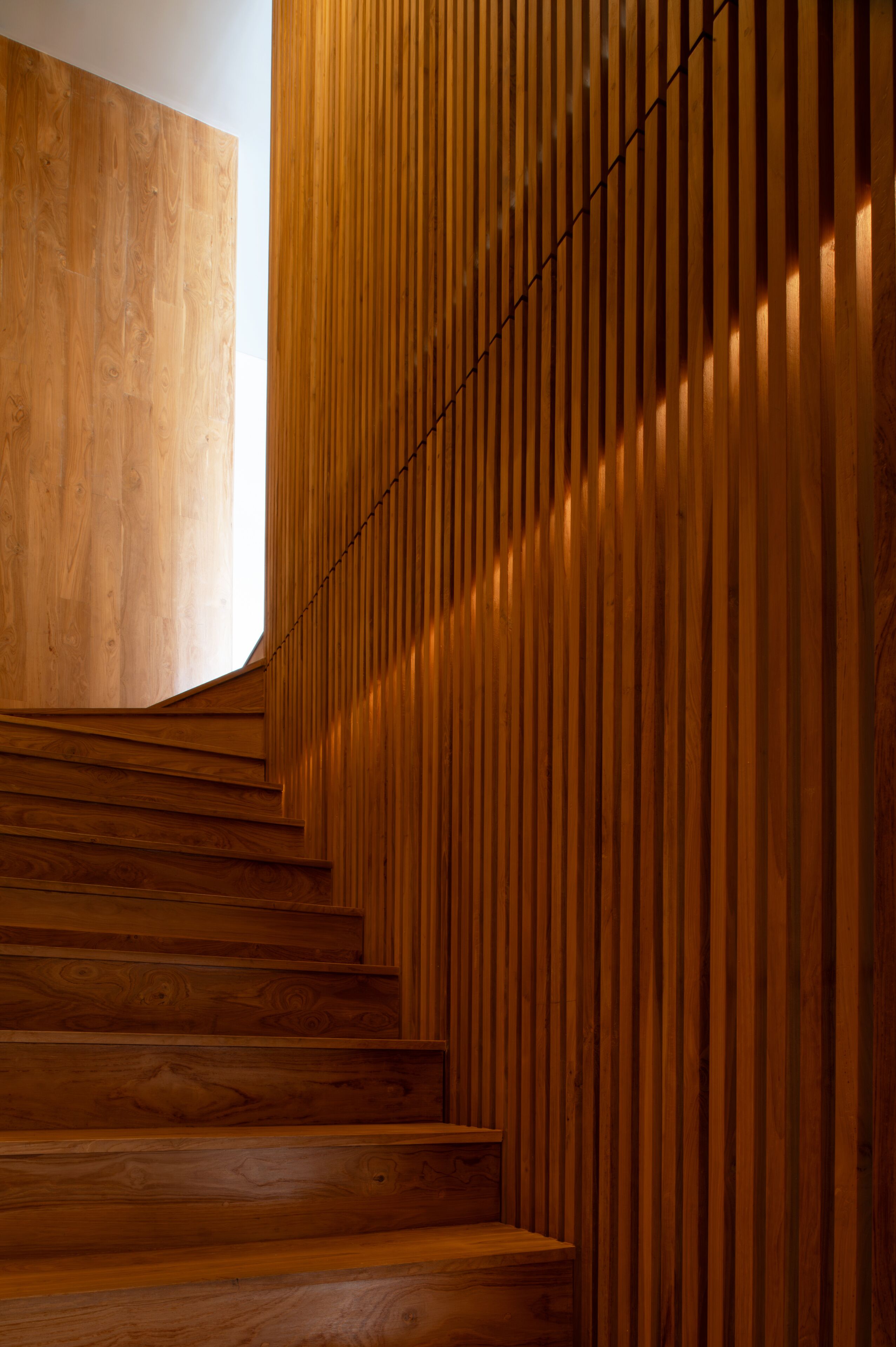 A wooden staircase with a modern design, leading to a higher level.