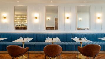 Un interior de restaurante moderno con asientos tapizados en azul, mesas redondas y sillas marrones.