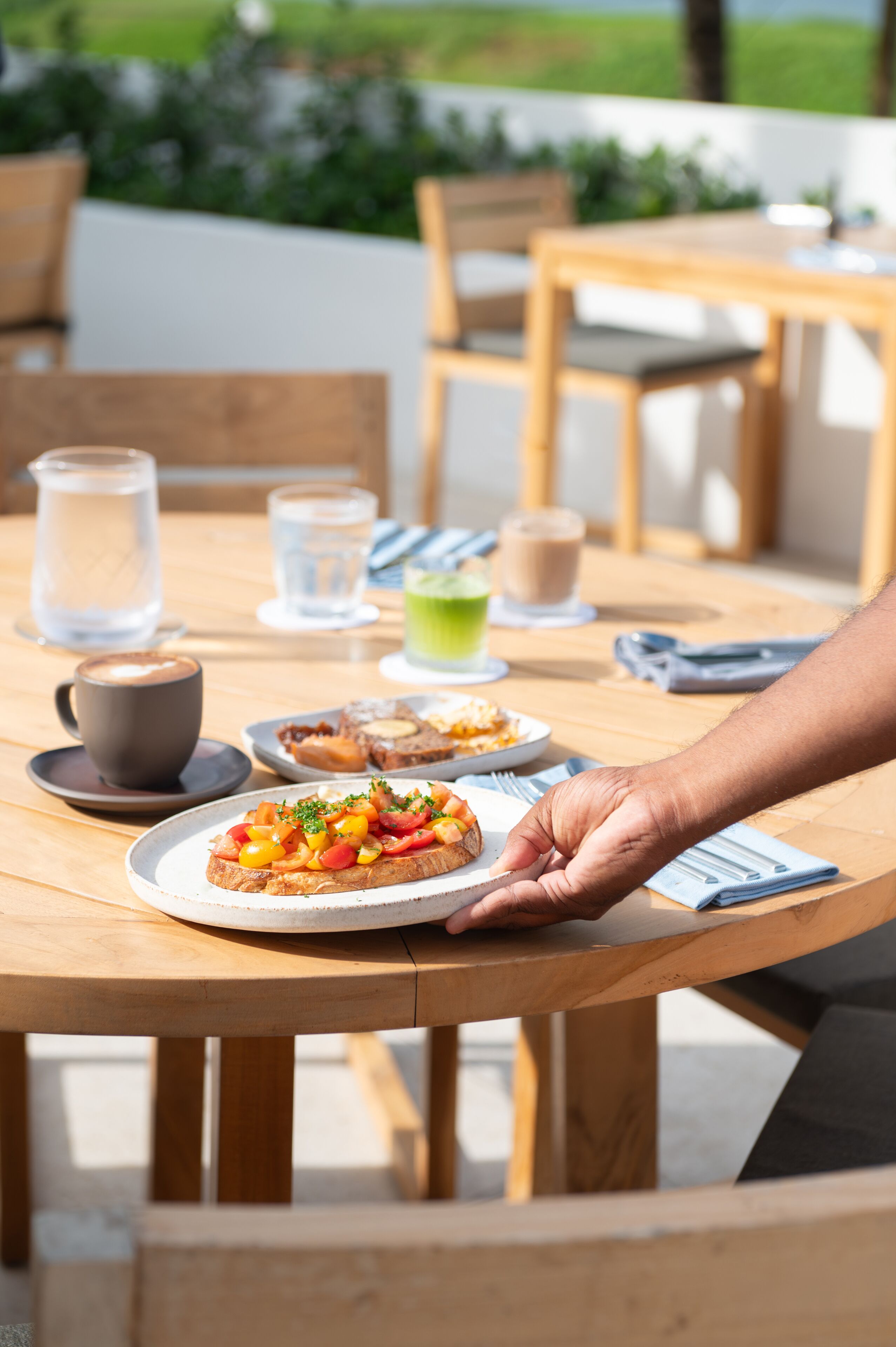 A wooden table with a plate of food, a cup, and a pitcher of water.