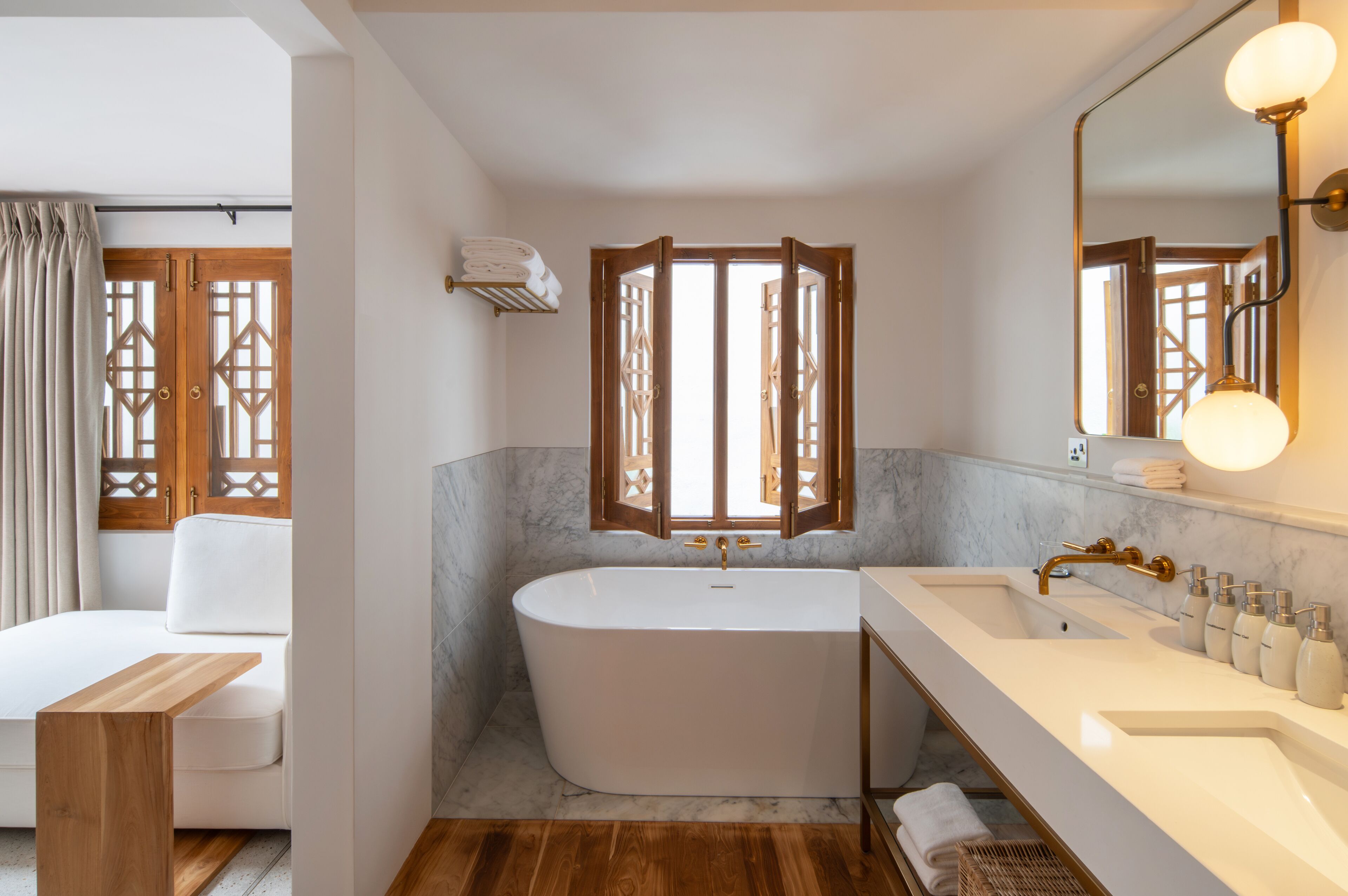 A modern bathroom with a freestanding bathtub, a large mirror, and a vanity with toiletries.