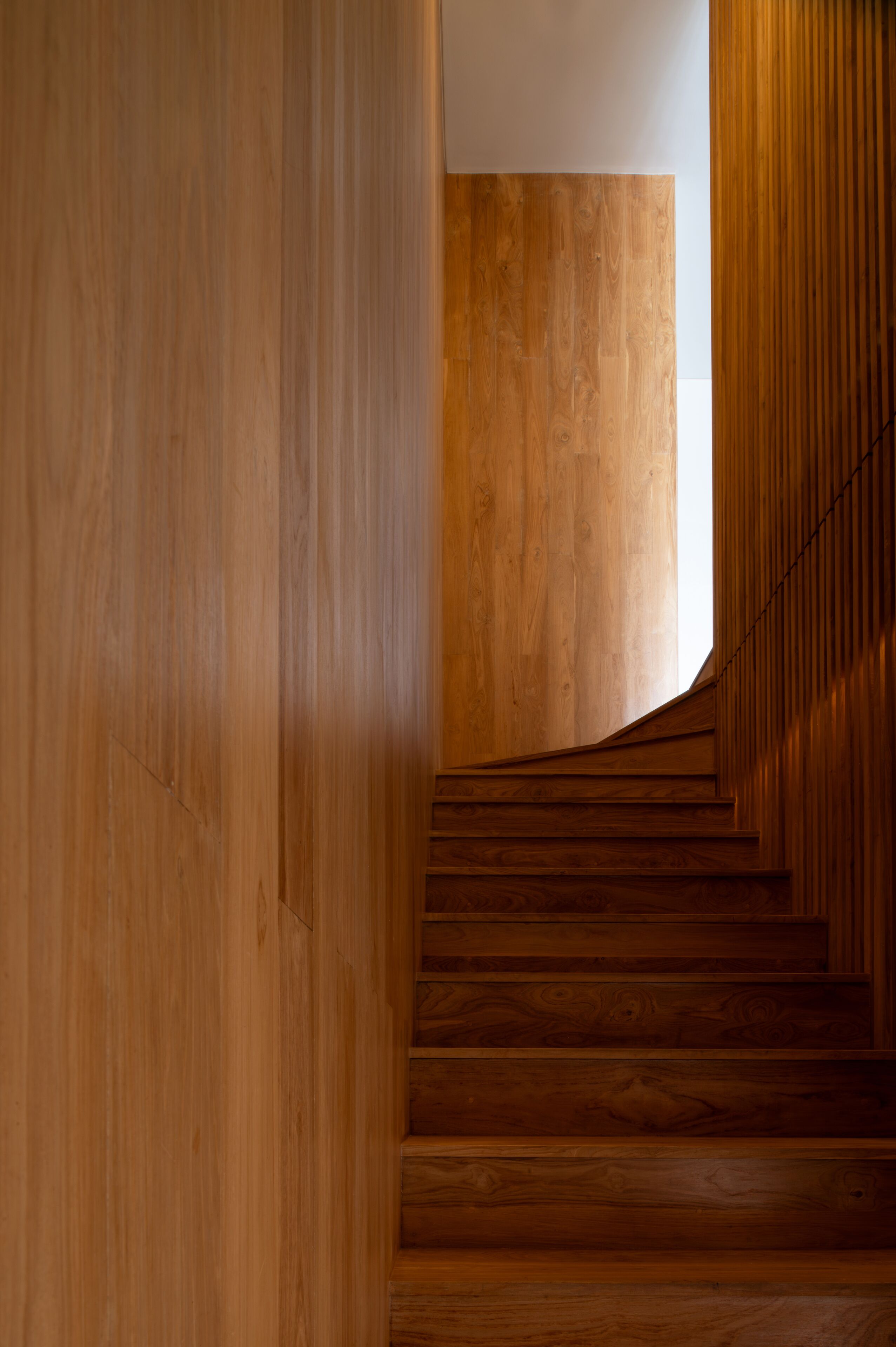 Una escalera de madera con diseño moderno que sube a un piso superior.