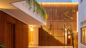 Ein modernes Interieur mit einer Holzhakenschrankwand, einer Topfpflanze und einer Treppe zu einer oberen Ebene.