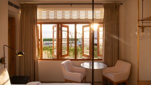 Ein Hotelzimmer mit Bett, zwei Stühlen, einem runden Tisch und einem Fenster mit Vorhängen.