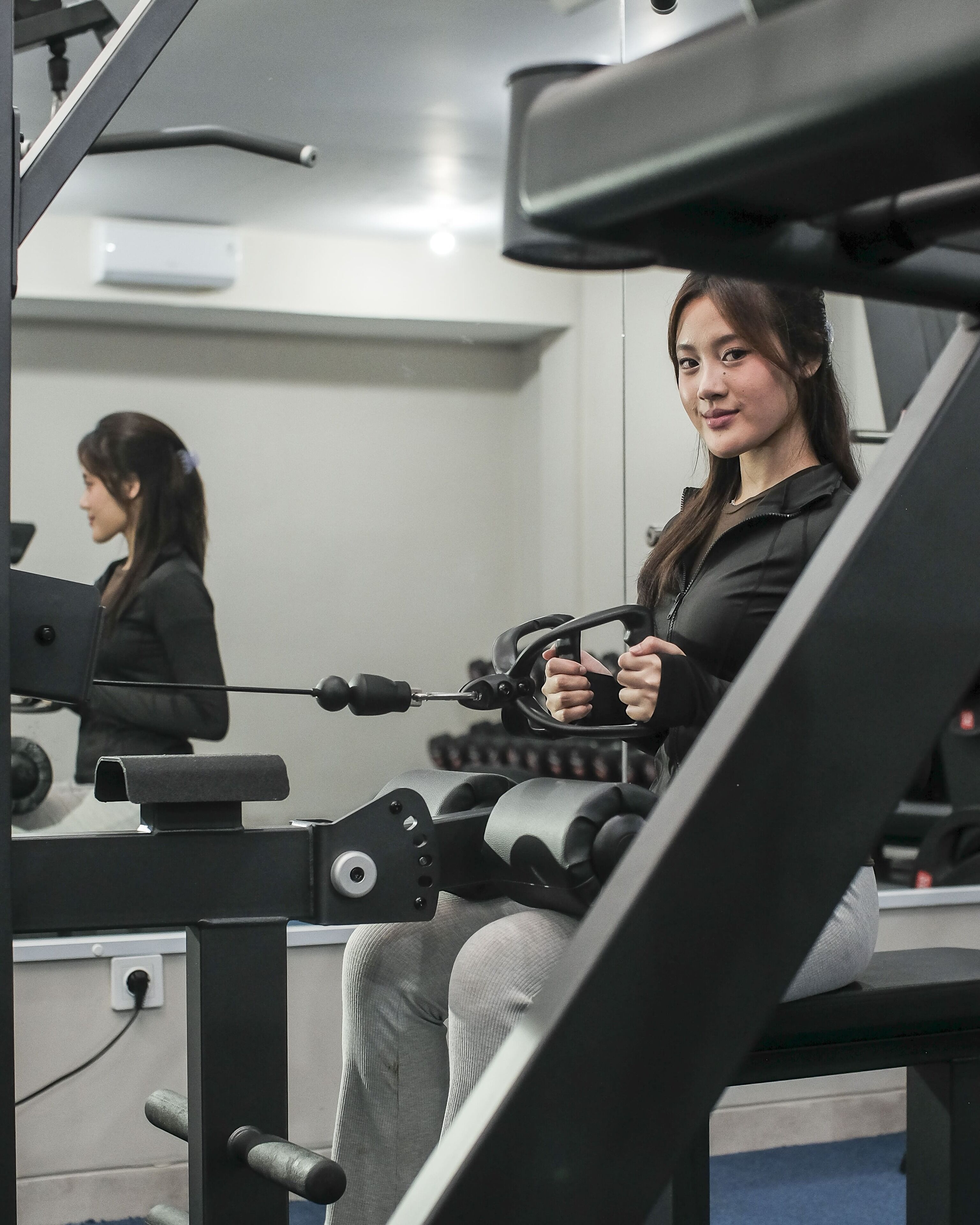 Een sportschool met fitnessapparatuur, waaronder een roeimachine en een bankdrukpers.