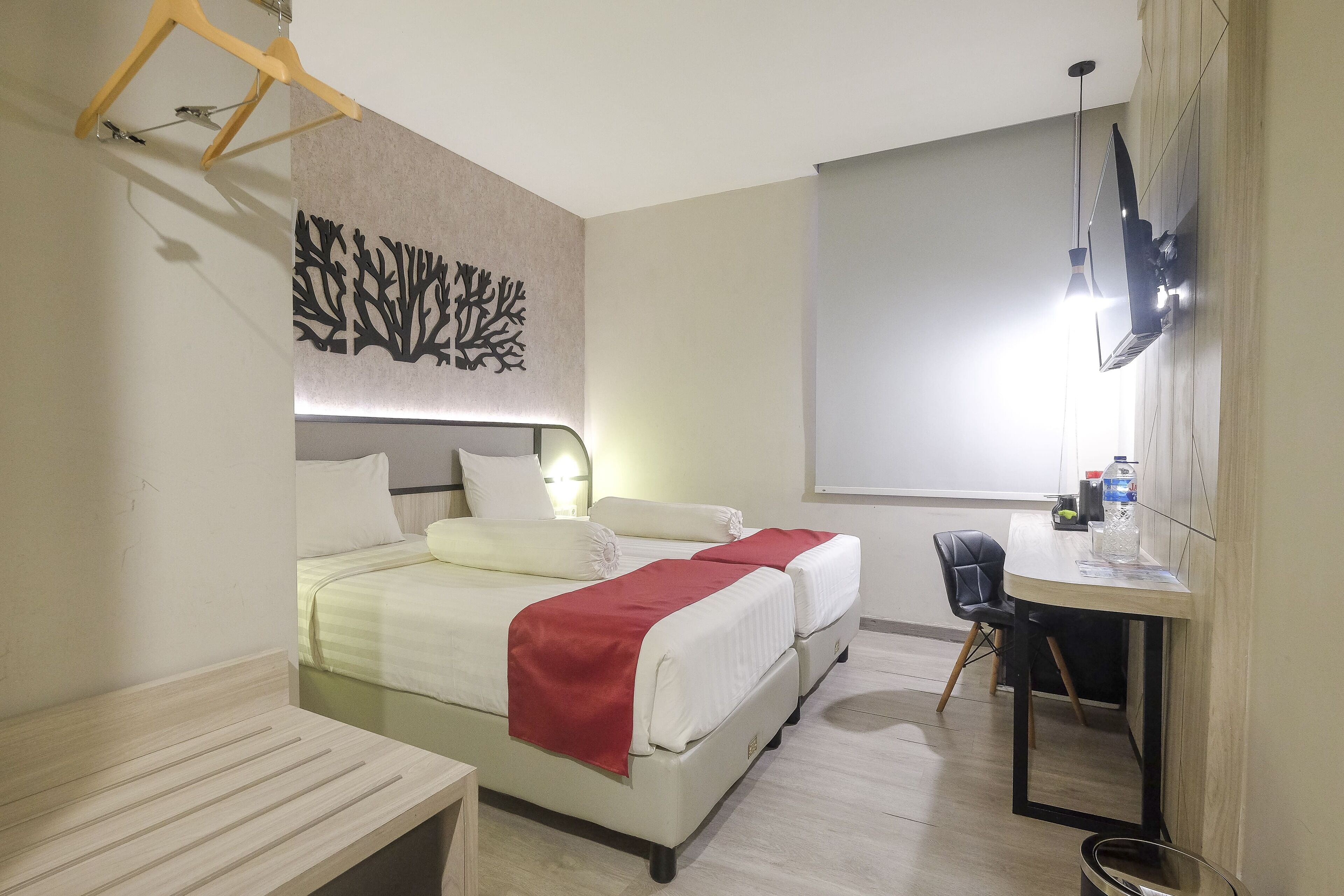 A hotel room with a bed, bedside table, and a desk with a chair.