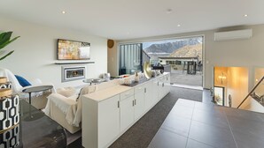 Een moderne woonkamer met een groot raam, een open haard en uitzicht op bergen.