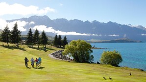 Een golfbaan met een meer, bergen en bomen.