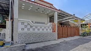 Un edificio con fachada de tejas, una entrada porticada y un área cubierta con techo de metal.