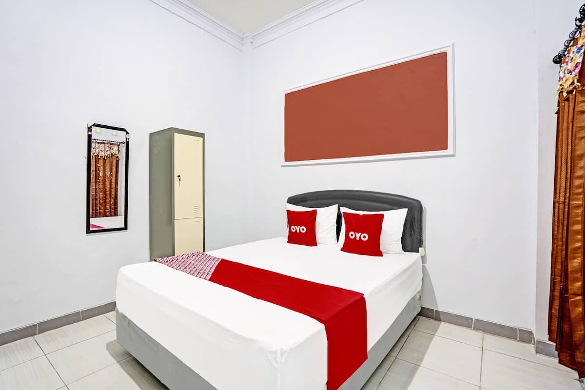 Una habitación de hotel con cama, armario, un cuadro enmarcado y una pared grande y despejada.
