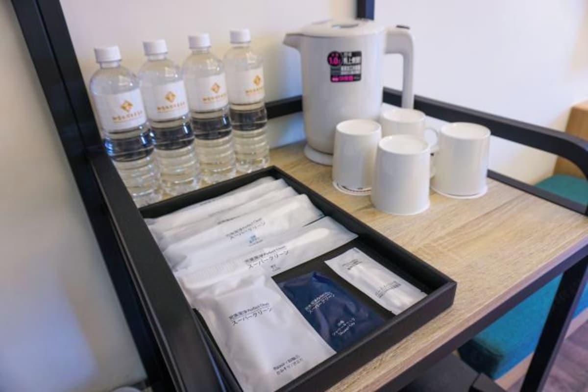 Una bandeja con botellas de agua, tazas de café y sobres de té y aperitivos.