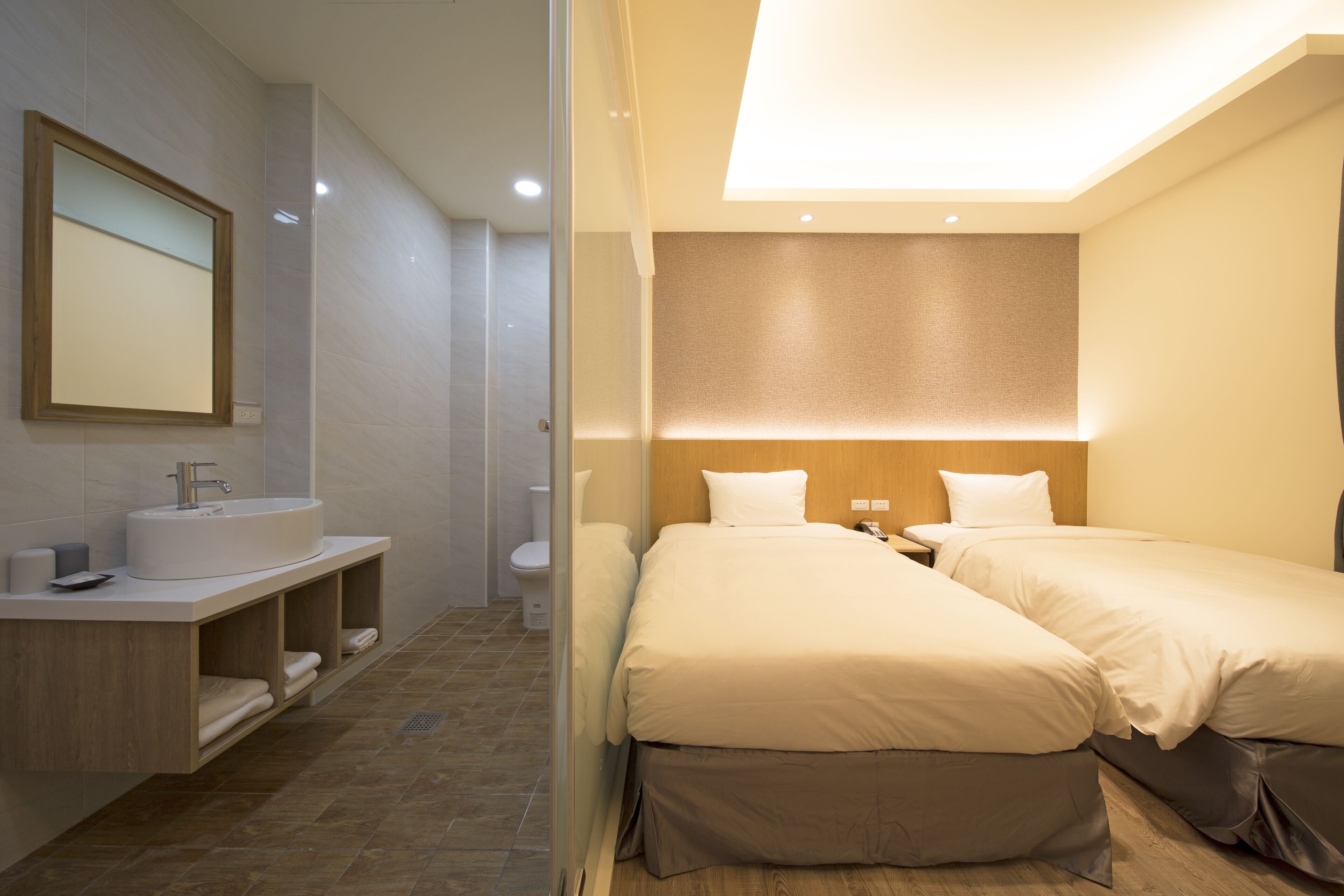 Una habitación de hotel moderna con una cama grande, una mesita de noche, un lavamanos empotrado y un espejo.