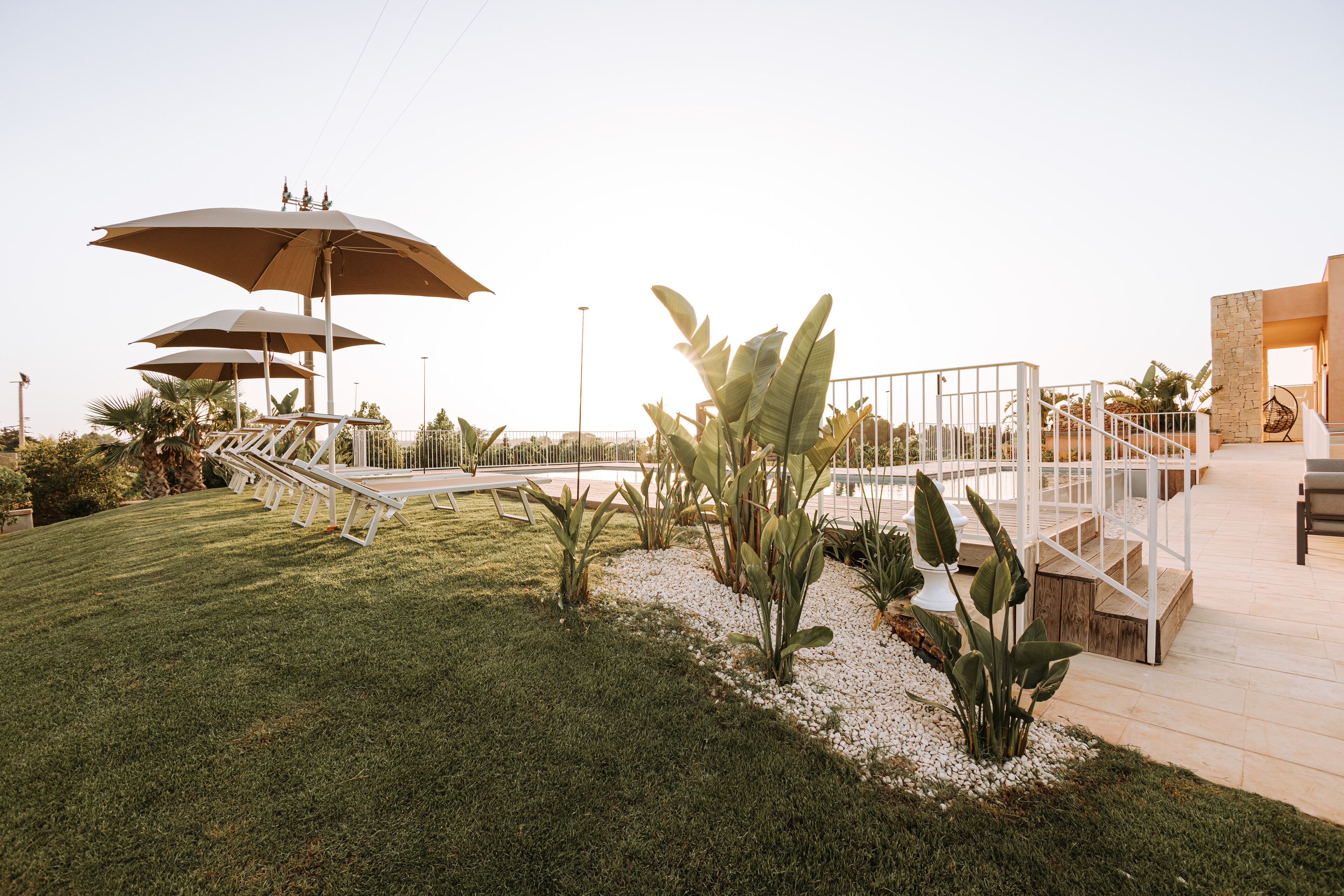 A landscaped outdoor area with a pathway, seating, and large umbrellas.