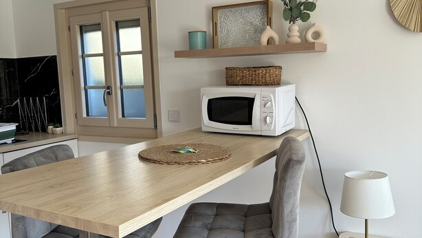 A modern kitchen with a wooden table, a microwave, and a chair. - Quiet studio with terrace (Rougemont)