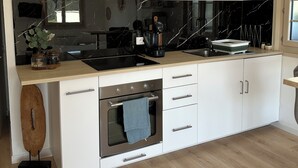 A modern kitchen with a built-in oven, a sink, and a countertop with various appliances. - Quiet studio with terrace (Rougemont)