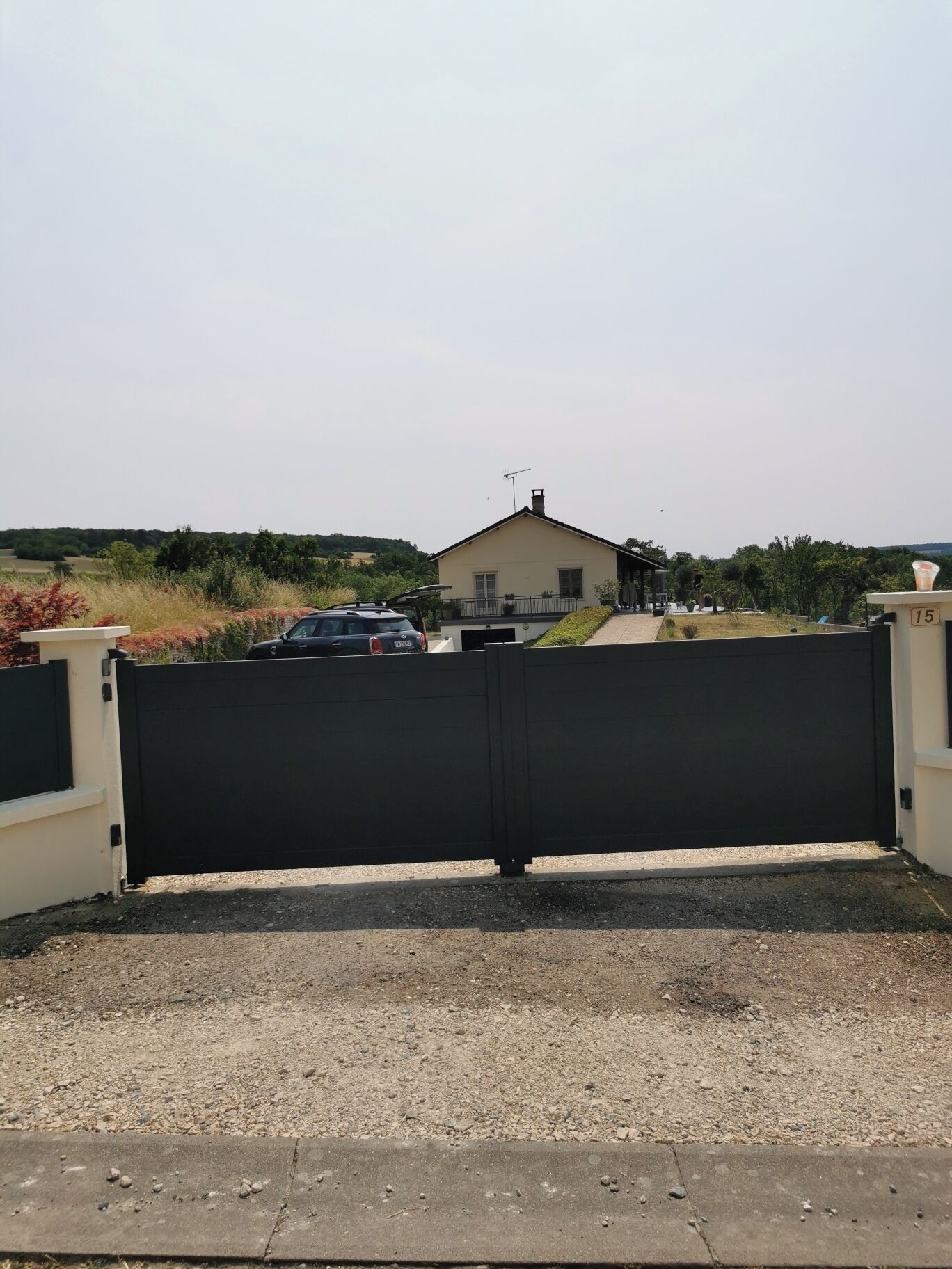 A gated entrance to a property with a house in the background.