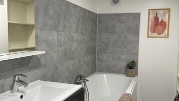 Une salle de bain moderne avec deux lavabos, une baignoire et une douche.