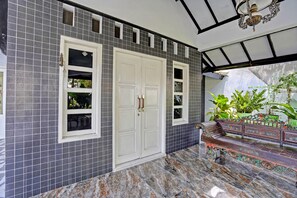 A room with a tiled wall, a white door, and a bench with decorative railings. - OYO 91868 Nusa Indah Guest House Syariah (Lamongan)