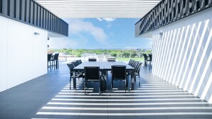 An outdoor patio with a long table and chairs, surrounded by white walls and a patterned ceiling. - Luxury Apartment in Dickson, Canberra (Dickson)