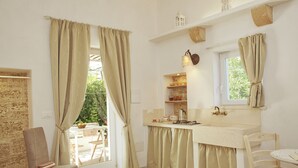 A cozy room with a bed, a chair, a table with towels, a window with curtains, a sink, and a small shelf with items. - Italy Apulia Salento, Lecce, Ancient villa countryside, swimming pool relaxation (parabita)