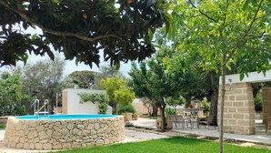 A stone pool surrounded by grass, trees, and outdoor furniture. - Italy Apulia Salento, Lecce, Ancient villa countryside, swimming pool relaxation (parabita)