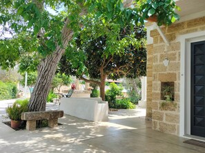 A courtyard with a stone bench, a potted plant, and a wall-mounted light fixture. - Puglia Salento, Lecce, villa countryside Ncettamia - Swimming pool relaxation (parabita)