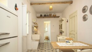 A narrow kitchen with a tiled floor, a wooden table with a lace doily, and a refrigerator labeled "AKAI". - Italy Apulia Salento, Lecce, Ancient villa countryside, swimming pool relaxation (parabita)