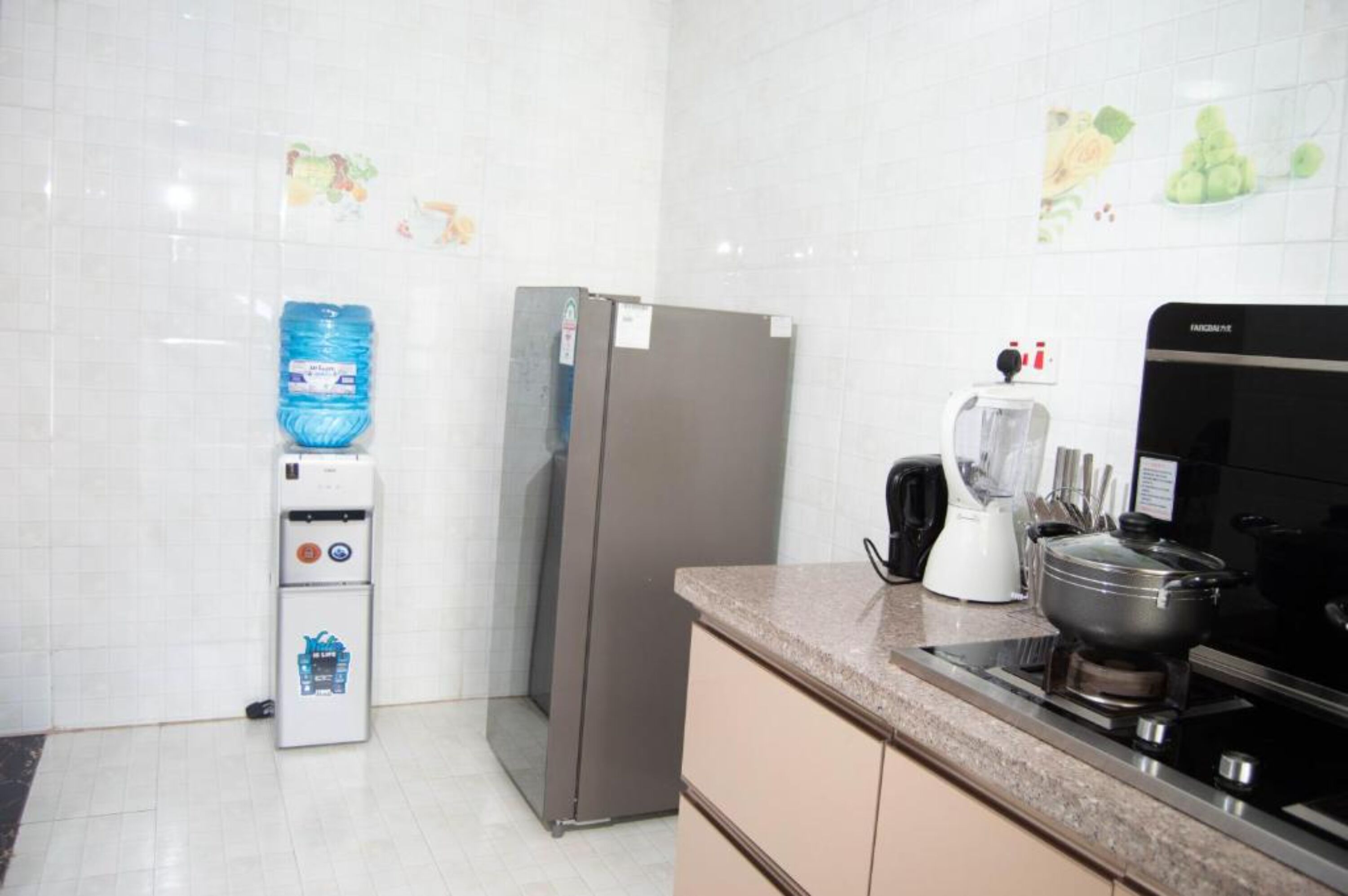 Une cuisine équipée d’un réfrigérateur, d’un distributeur d’eau, d’une machine à café et d’une cuisinière.