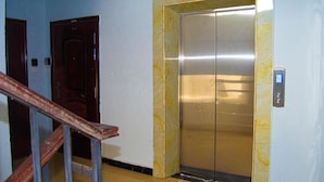 En elevator med en marmorvæg og et digitalt kontrolpanel.