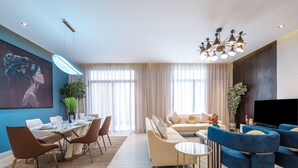 A modern living room with a dining area, a sofa set, a TV, and a large painting on the wall. - Mabaat - Hittin - 519 (Riyadh)