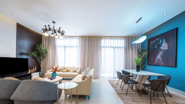 A modern living room with a sofa, coffee table, TV, and dining area with chairs and a table. - Mabaat - Hittin - 519 (Riyadh)