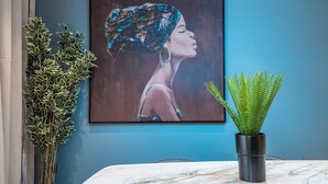 A framed painting on a blue wall, a potted plant, and a marble table. - Mabaat - Hittin - 519 (Riyadh)