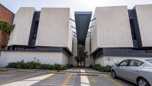 A modern building with a symmetrical facade, a central entrance, and a parking area with marked spaces. - Mabaat - Hittin - 519 (Riyadh)