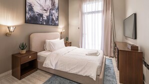 A modern bedroom with a large bed, bedside tables, a mounted TV, and a large abstract painting. - Mabaat - Hittin - 519 (Riyadh)