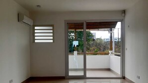 A spacious room with a large sliding glass door leading to a balcony. - La Falaise Seafront Villa (Flic En Flac)