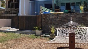 A two-story house with a balcony, a small attached garage, and a hammock in the yard. - La Falaise Seafront Villa (Flic En Flac)